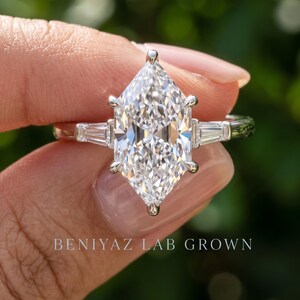 Dutch marquise diamond engagement ring held by hand showing F VS1 lab grown center and symmetrical side stone design