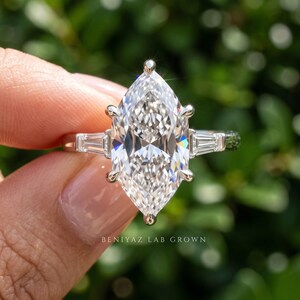 Macro front view of 2 carat Dutch marquise lab grown diamond engagement ring held between fingers with side stones