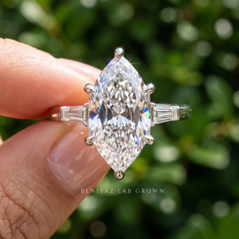 Macro front view of 2 carat Dutch marquise lab grown diamond engagement ring held between fingers with side stones