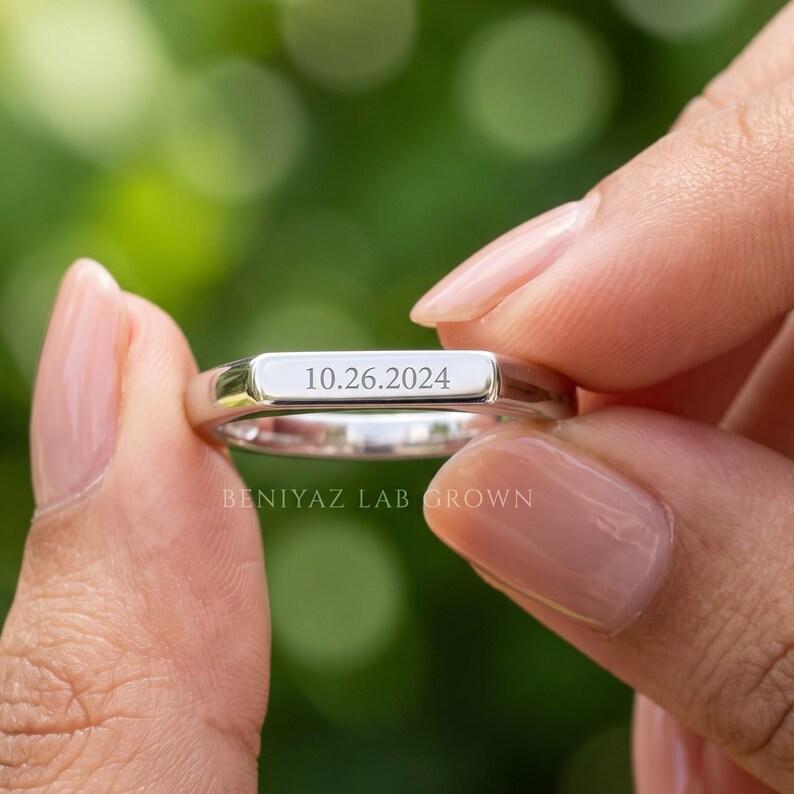 Close up hand view of a personalized engraved wedding ring featuring a custom date inscription on a polished minimalist band