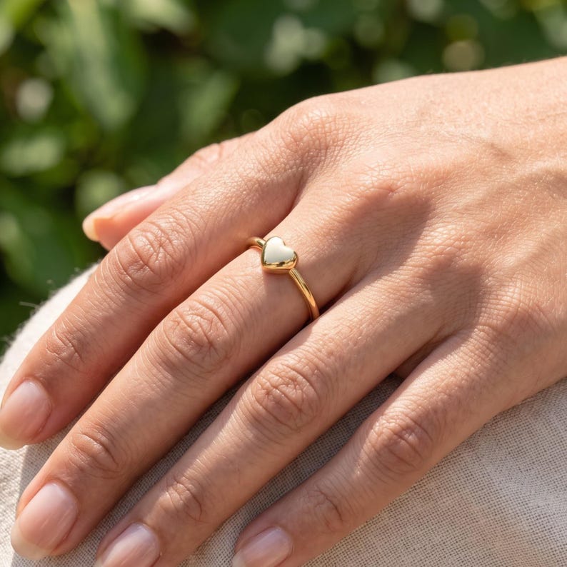 Side profile of love ring showing the rounded heart centerpiece and slim polished shank.