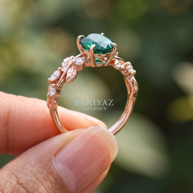 Nature inspired ring side view with oval emerald center, branch style shoulders and sparkling round gemstone accents.