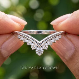 Detailed front view of curved wedding band for women with round moissanite stones and nesting chevron silhouette.