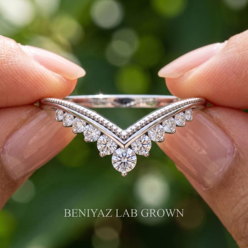 Detailed front view of curved wedding band for women with round moissanite stones and nesting chevron silhouette.