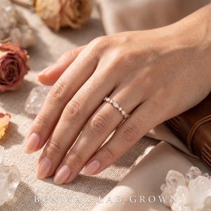 Woman wearing a dainty marquise and round lab grown diamond wedding band on finger in a bridal lifestyle setting
