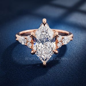 Marquise lab grown diamond cluster engagement ring displayed on blue velvet with botanical inspired side accents