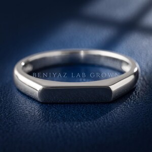 Polished flat top signet ring shown at an angled view with a slim tapered band and modern minimalist design.