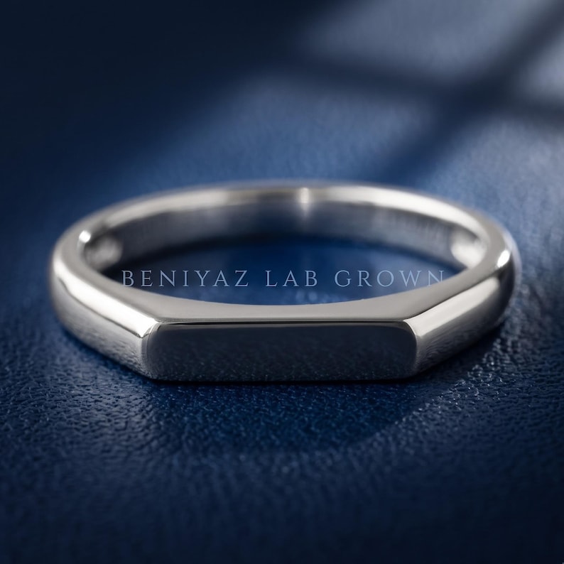 Polished flat top signet ring shown at an angled view with a slim tapered band and modern minimalist design.