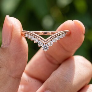 Front close up of chevron wedding band with round moissanite stones graduating toward the center V point.
