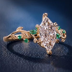 Angled side view of a Dutch marquise lab grown diamond engagement ring with green accents, leaf details and sculpted botanical shoulders.