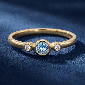 Dainty three stone ring in white gold with a round blue gemstone center and two natural diamond accents.