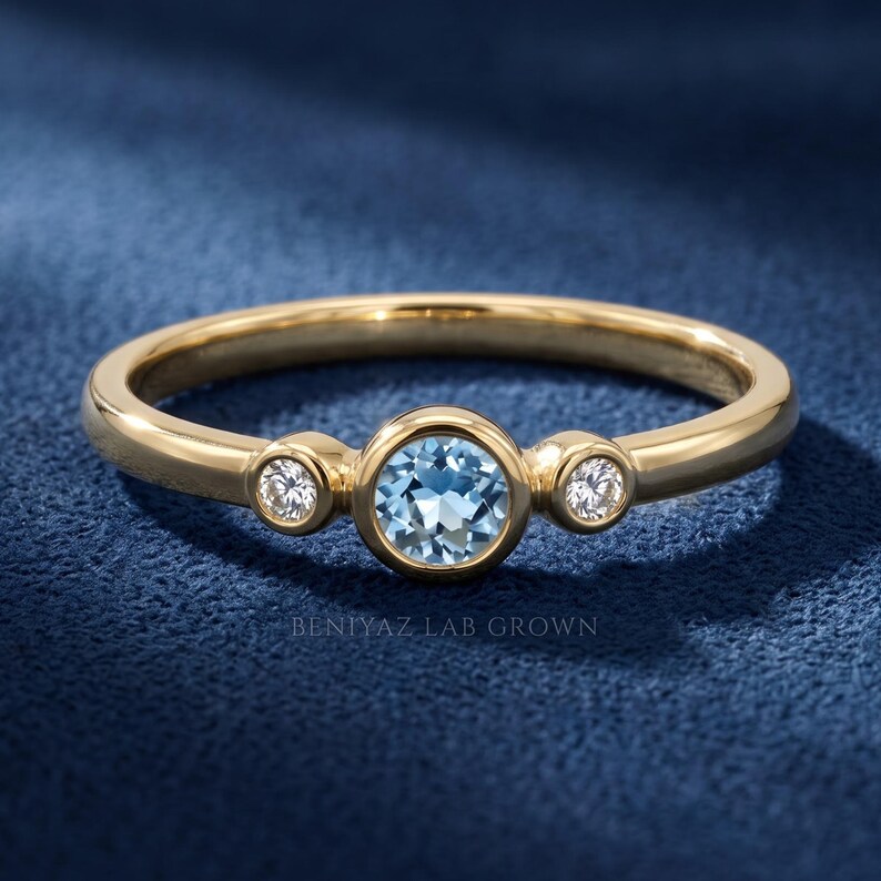 Dainty three stone ring in white gold with a round blue gemstone center and two natural diamond accents.