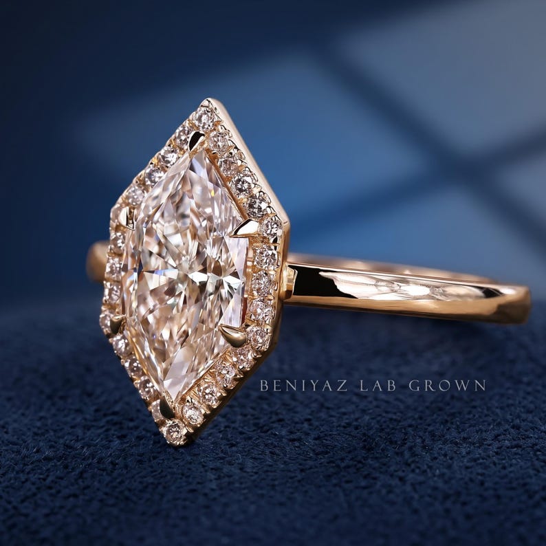 Angled view of a geometric Dutch marquise halo engagement ring showing the elongated lab grown diamond center and slim gold band.