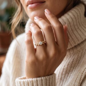 Dainty nature inspired engagement ring worn on a woman’s hand, showing the round brilliant diamond and delicate leaf design.