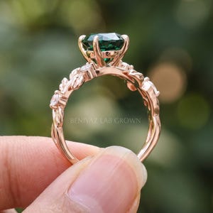 Rear view of oval emerald engagement ring showing the raised prong setting, open gallery and slim botanical band.
