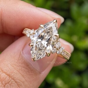 Side profile of a vintage inspired marquise engagement ring on a dark blue background showing the elevated prong setting.