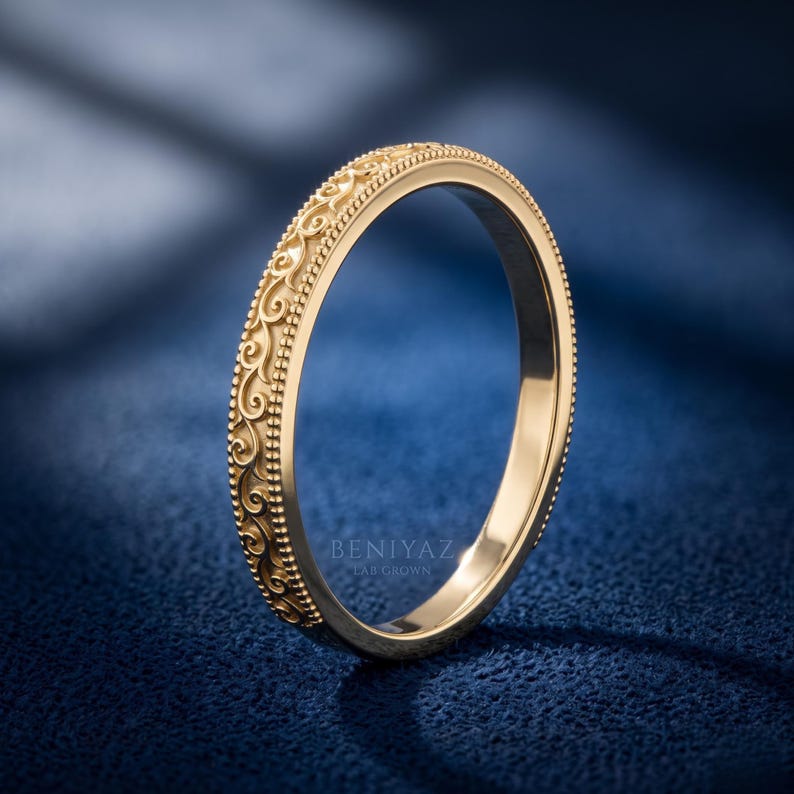 Yellow gold engraved scroll wedding band shown in side angle view, delicate milgrain ring, minimalist antique inspired stacking wedding band.