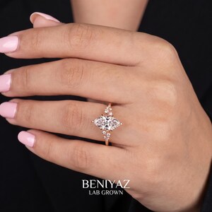 Marquise diamond engagement ring worn on a woman’s hand, showing the elegant vintage inspired cluster design.