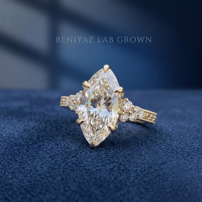 Side view of a marquise lab grown diamond engagement ring showing the raised prong setting and diamond accented yellow gold band.