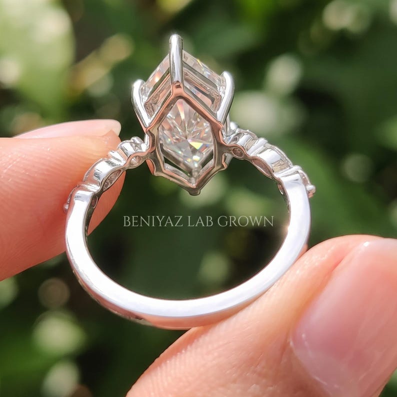 Side and rear profile of a Dutch marquise lab grown diamond engagement ring held between fingertips, displaying the elevated solitaire basket, slim band and underside of the diamond setting.