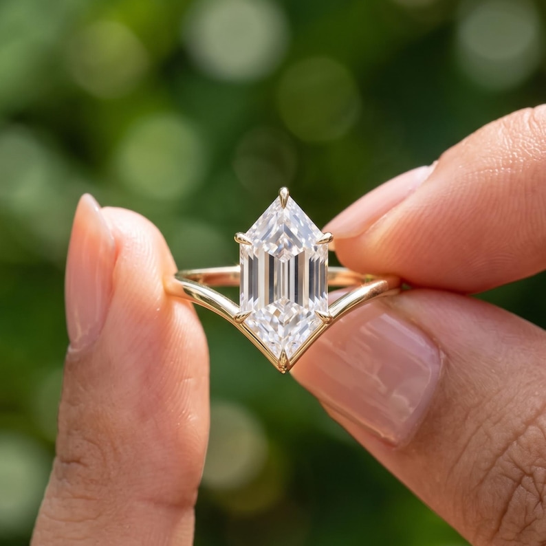 Close up hand held view of a Dutch Marquise lab grown diamond solitaire ring with an elongated center stone and gold band.