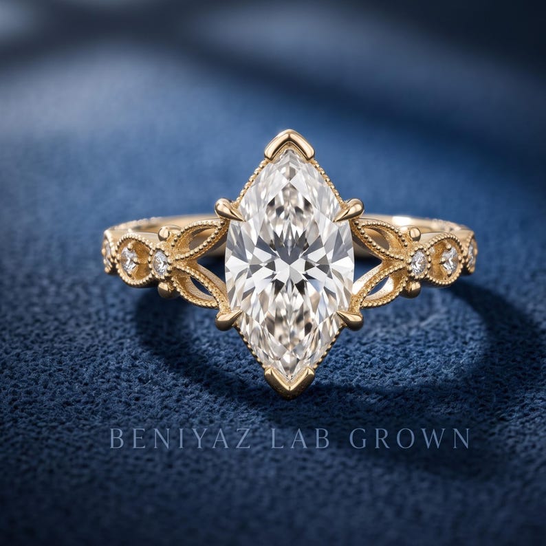 May include: A gold ring featuring a large marquise-cut center stone held by prongs, flanked by intricate filigree metalwork and small round accent stones along the band. The text BENIYAZ LAB GROWN is visible at the bottom of the image.