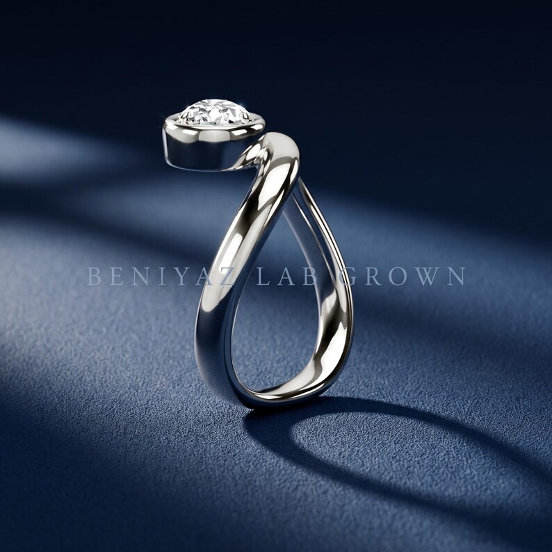 Pear diamond sculptural ring shown with available metal options, featuring a smooth organic bypass silhouette.