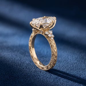 Side profile of a 3 CT marquise lab grown diamond ring showing the raised centre stone and pave set yellow gold band.