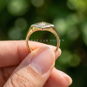Promise ring style diamond signet with single star set round diamond, elongated gold face and delicate tapered band.