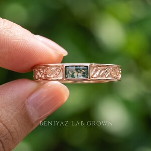 Puede incluir: Un anillo de oro rosa con una piedra de &aacute;gata musgosa rectangular engastada en el centro. La banda est&aacute; decorada con un patr&oacute;n de hojas en relieve a ambos lados de la piedra. El texto BENIYAZ LAB GROWN aparece en la parte inferior.
