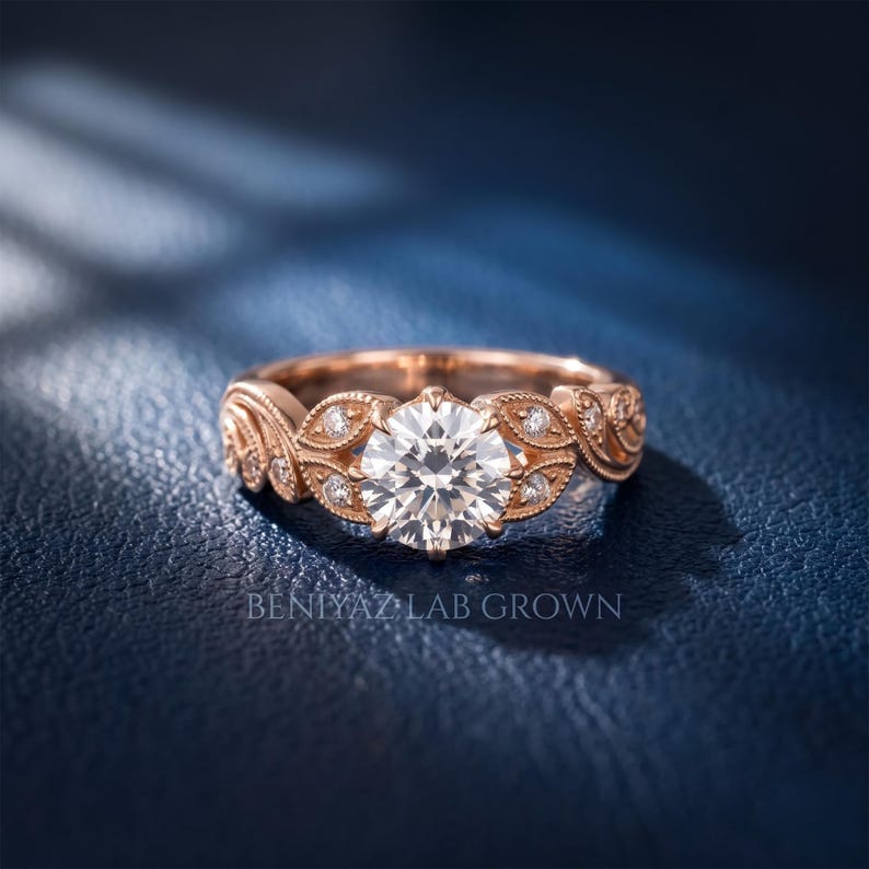 Close-up rose gold lab grown diamond engagement ring with a round brilliant center diamond, antique style leaf design, milgrain details and accent stones along the shoulders.