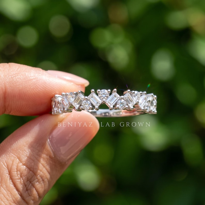 Hand holding a 0.74 CT baguette lab grown diamond wedding band in gold, featuring a half eternity cluster design and sparkling geometric diamond setting
Baguette wedding band with mixed baguette, round and marquise lab grown diamonds in a half eternity white gold band