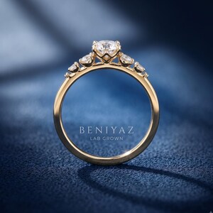 Yellow gold five stone lab grown diamond engagement ring shown upright, highlighting the raised round centre diamond and graduated side stones.