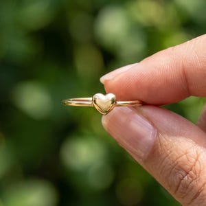 Close side view of stackable love ring with raised heart design and slim polished band for everyday wear.