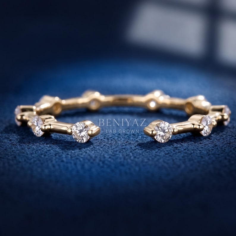May include: A gold open-style ring featuring a series of evenly spaced, round, clear lab-grown diamonds set along the band. The text BENIYAZ LAB GROWN is visible in the center of the ring, which has a polished metallic finish and a circular shape.