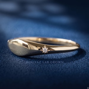 Side profile of a tapered yellow gold signet ring showing the low domed face and slim polished band.