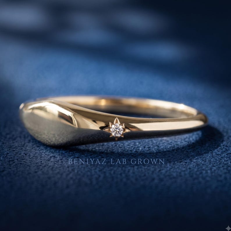 Side profile of a tapered yellow gold signet ring showing the low domed face and slim polished band.