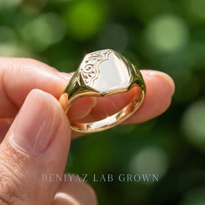 Side view of personalized oval signet ring with vintage floral openwork shoulders, polished face and tapered signet shank