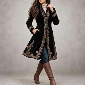 May include: A black velvet coat featuring long sleeves, a high collar, and a front button closure. The garment is adorned with intricate gold-toned embroidery along the front placket, cuffs, and hemline, paired with dark blue denim jeans.