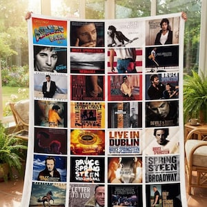 May include: A rectangular quilt featuring a grid of thirty-two distinct Bruce Springsteen album covers. The design includes various photographic portraits, concert imagery, and text-based album titles such as Nebraska, The Rising, and Live in Dublin.