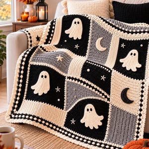 Puede incluir: Una manta de ganchillo con diseño de patchwork en negro, blanco y gris. Los cuadrados están decorados con apliques de fantasmas blancos, lunas crecientes y estrellas pequeñas. El borde presenta un patrón de punto bobble texturizado.