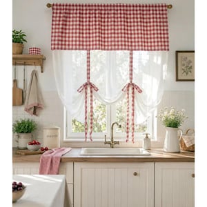 May include: A window valance featuring a red and white gingham check pattern at the top, with two attached fabric ties that gather the sheer white curtain panels below into a draped, scalloped shape, suspended from a simple horizontal rod.