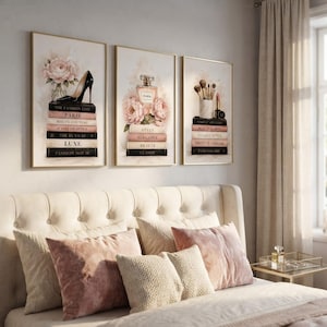 The set of three fashion wall art prints displayed above a cozy blush and cream bedroom headboard.
