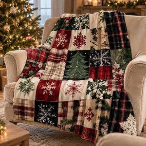 Peut inclure: Un plaid doux présentant un motif patchwork composé de carrés sur le thème des fêtes. Le design inclut des carreaux rouges et verts, des flocons de neige blancs sur fond rouge ou noir, et un sapin de Noël vert sur un carré noir.