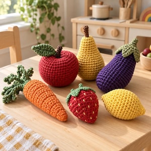 May include: A collection of six crocheted play food items including a red apple with a green leaf, a yellow pear, a purple eggplant with a green stem, an orange carrot with green tops, a red strawberry, and a yellow lemon on a wooden table.