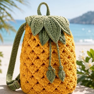 May include: A crochet backpack shaped like a pineapple, featuring a textured yellow body with a repeating shell stitch pattern. The top flap is adorned with green crocheted leaves, and the bag includes green straps and a drawstring closure.