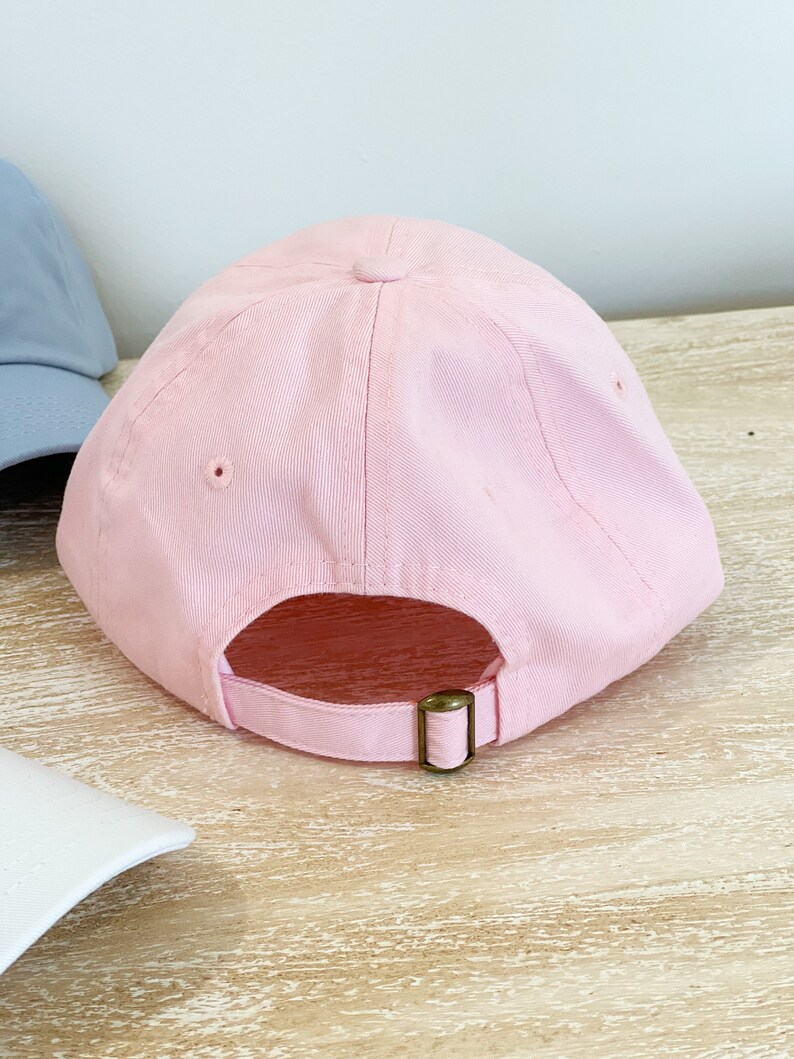 May include: A pink baseball cap with a brown adjustable strap in the back.