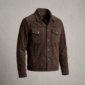 May include: A dark brown suede jacket featuring a classic collar, long sleeves, and a button-up front. The garment includes two chest pockets with buttoned flaps, vertical seam detailing, and matching brown buttons throughout the design.