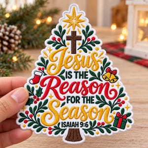 May include: A white embroidered patch shaped like a Christmas tree featuring a brown cross, a yellow star, and the text "Jesus is the reason for the season" in red and yellow. It includes green holly, red berries, a stocking, bells, and a gift.