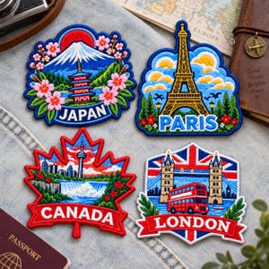 May include: Four embroidered patches featuring travel themes. The Japan patch shows Mount Fuji and a pagoda. The Paris patch depicts the Eiffel Tower. The Canada patch is shaped like a maple leaf with a city skyline. The London patch shows Tower Bridge and a red bus.